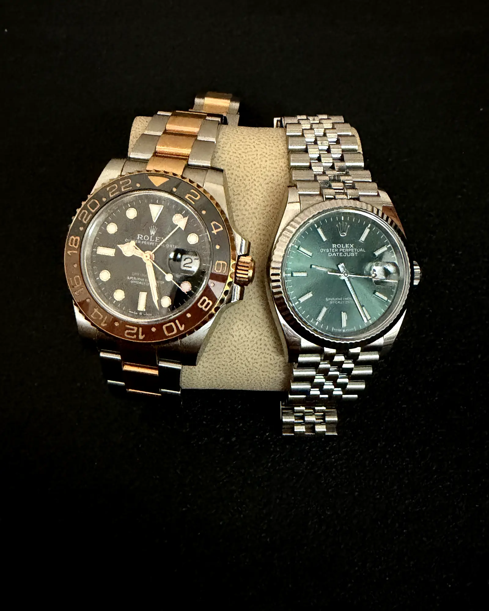 Dos relojes de pulsera de lujo sobre un cojín de piel con fondo oscuro